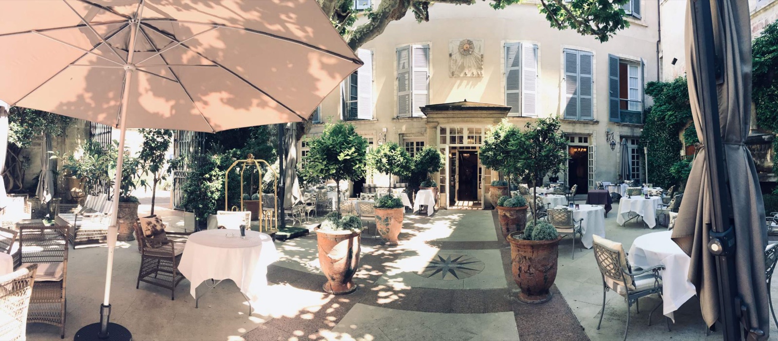 La cour d'honneur de l'hôtel, tables dressées sous les platanes