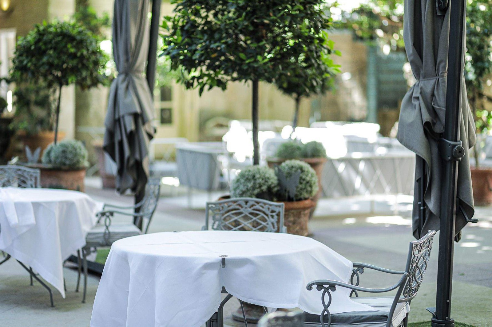 Les tables du restaurant dressées dans la cour, sous les arbres
